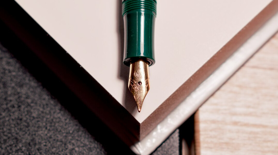 Open handwritten notebook with a fountain pen