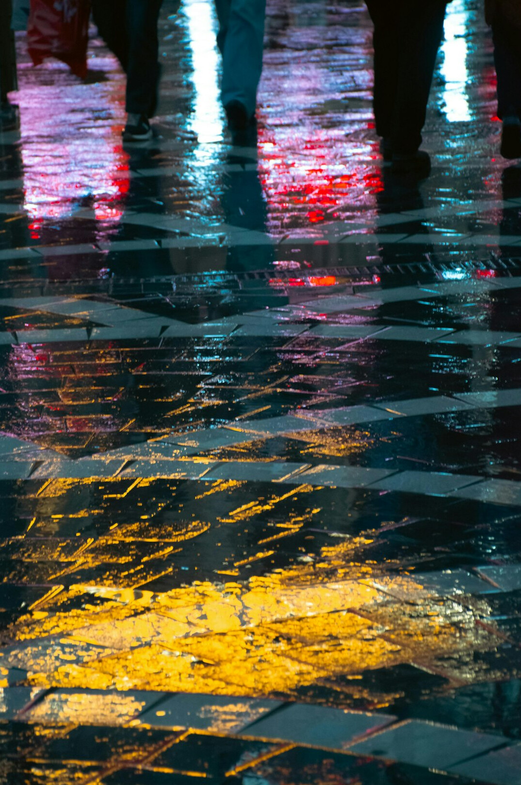City street at night reflecting neon lights on wet pavement